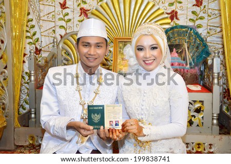 Indonesian bridal couples  showing their marriage book at the marriage ceremony event