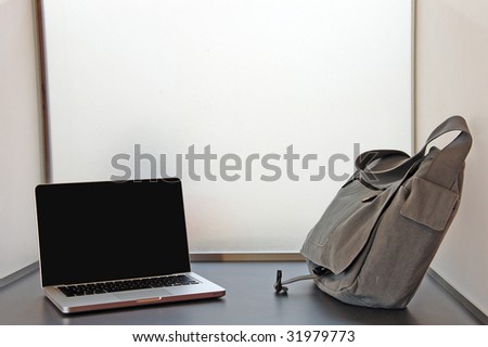An open laptop on a desk with a carrier bag