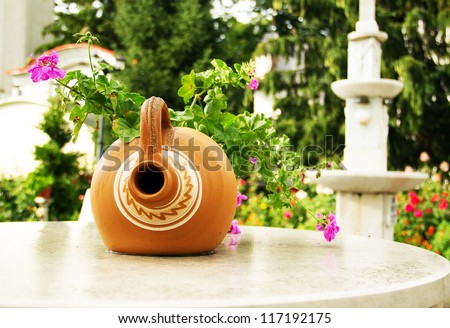 Very ancient well for the collection of rainwater and a vase of flowers