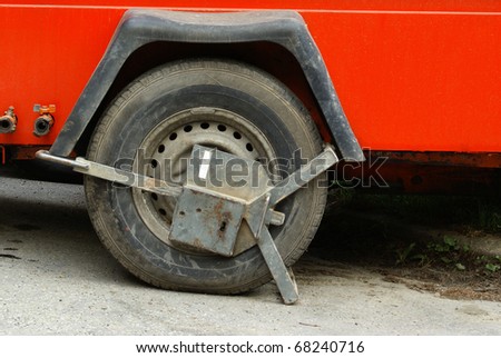 Clamped car wheel, blocked or locked red car, background