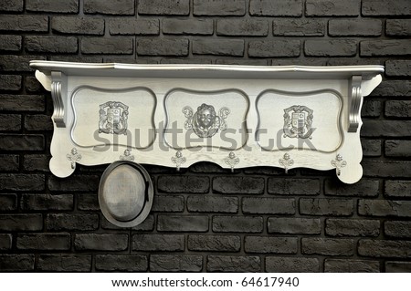 Vintage wooden silver rack with a hat on the black brick wall