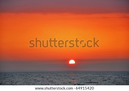 Red sunset with a sun.The sun disappears into the sea of metallic colors