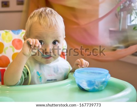 Baby boy eats with spoon himself