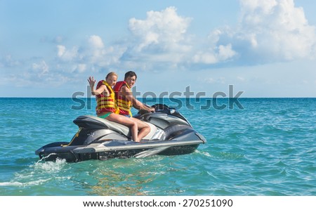 Happy girl and young man drive on scooter on sea