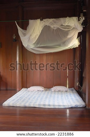 Simple bed and mosquito net in a Thai house