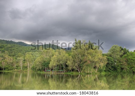 Overcast sky over a forest with restaurant beside a lake