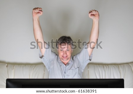 Man cheering whilst watching a television or computer screen