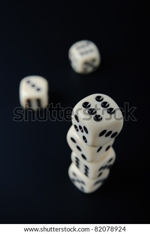 Top view of stacked dices and two single dices on black background