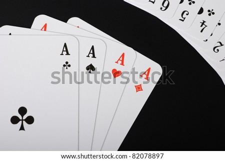 Four spread aces and additional playing cards in the right corner on black background