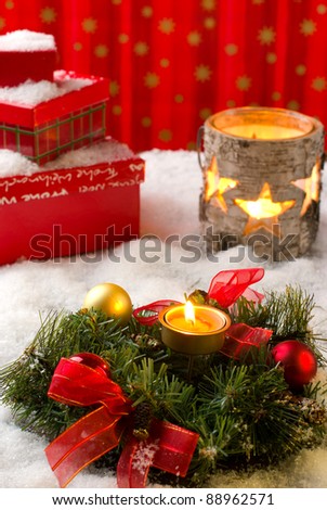 Christmas arrangement with wreath, balls, candles and gift boxes, covered with snow
