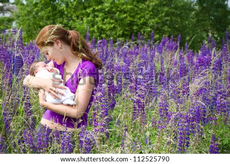 Young mother with her newborn baby in purple lupines field