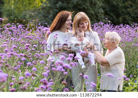 Great-grandmother, grandmother, mother holding a baby in a beautiful lavender field