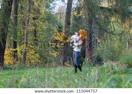 Beautiful woman and a baby girl walking in a forest among yellow trees