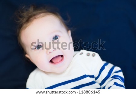 Laughing happy baby in a navy shirt on blue background