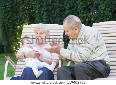 Grandparents playing with a little baby in the garden