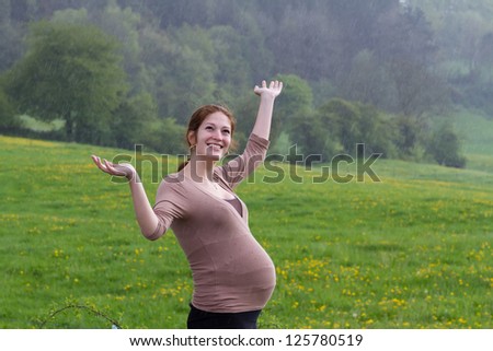 Young pregnant woman walking in the rain