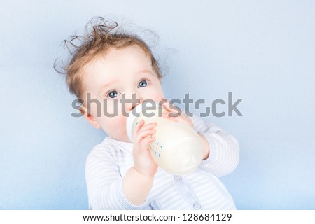 Cute Baby With A Milk Bottle On A Blue Blanket