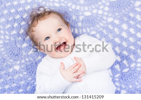 Happy laughing baby on a purple handmade knitted blanket