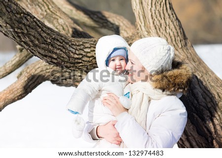 Young mother with a little baby walking in a snowy park