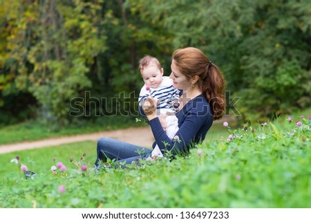 Beautiful young woman and her little bay relaxing in the garden