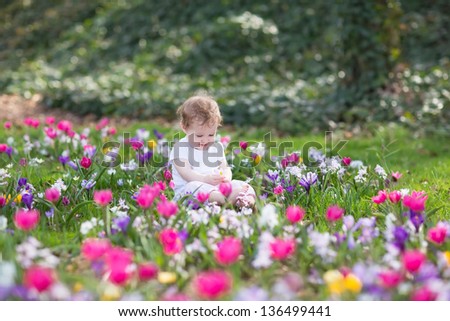 Beautiful funny baby girl playing in a field of flowers