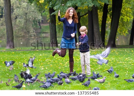 Mother and son feeding pigeons in a park