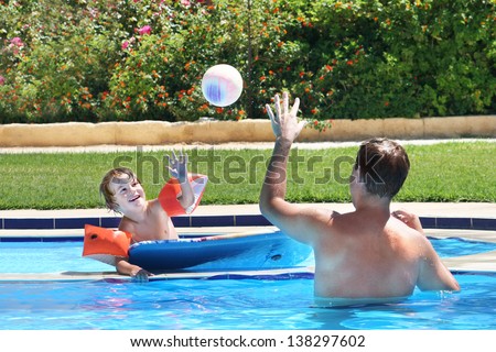 Father and son playing ball in a swimming pool