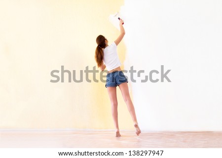 Young attractive woman painting walls in a new house