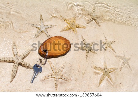 Hotel key with empty space on a wooden tag on a beach with star