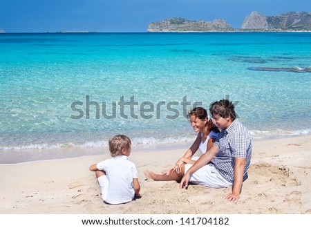 Young parent talking to their son sitting on a beautiful tropical beach