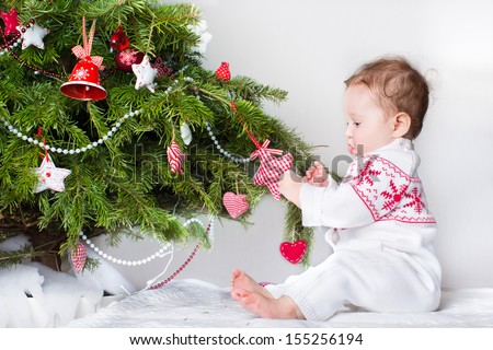 Sweet funny baby girl playing with Christmas tree decoration