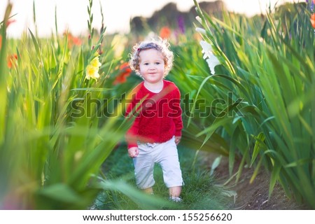 Cute little baby girl walking in a field on flowers on a farm on a nice warm autumn evening