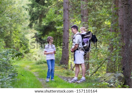 Young active father hiking with his school age son and baby daughter in a beautiful autumn forest