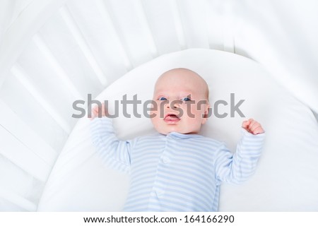 Sweet newborn baby boy in a white round crib