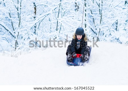 Little boy enjoying a sleigh ride in a snowy forest