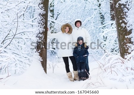 Young happy family with a little son walking and playing in a snowy park