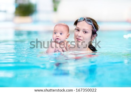 Young mother and her newborn baby having fun together in a swimming pool Young mother and her newborn baby having fun together in a swimming pool