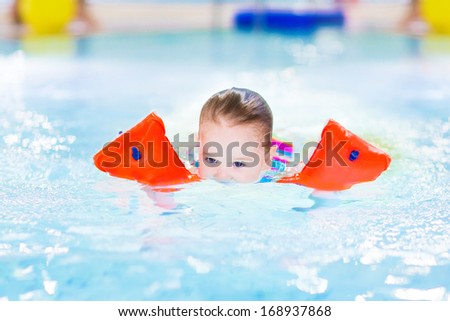 Cute toddler girl swimming in a pool with her face under water