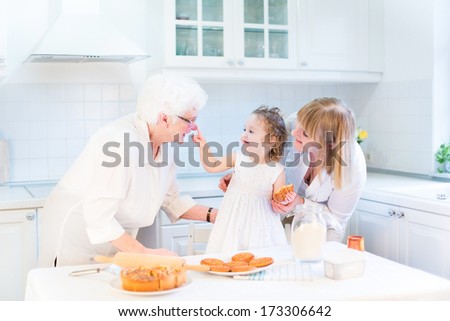 Funny toddler girl playing in a kitchen, having fun baking an apple pie with her grandmothers
