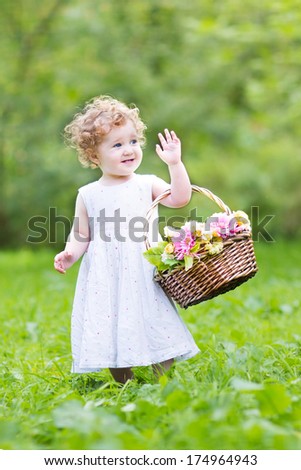 Funny toddler girl playing with a flower basket on Easter morning