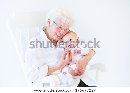 Beautiful grandmother singing to her newborn baby grandson sitting in a white rocking chair