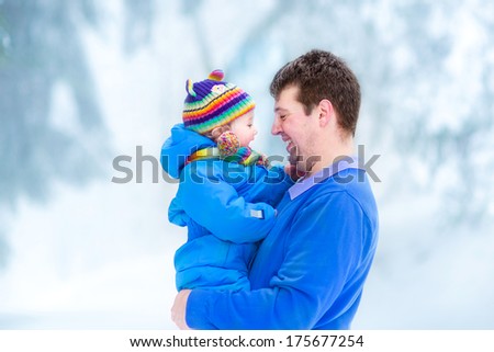 Young father playing with his funny baby in a snowy park