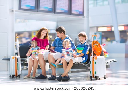 Big happy family with three kids traveling by airplane at Dusseldorf International airport, parents with teenager boy, toddler girl and little baby holding colorful luggage for summer beach vacation