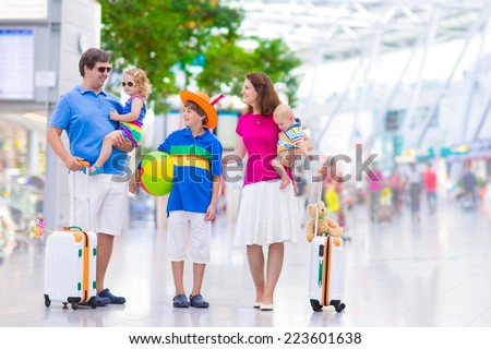 Big young family with three kids traveling by airplane at Dusseldorf International airport, parents with teenager boy, toddler girl and little baby holding colorful luggage for summer beach vacation