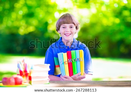 Child in school yard. Happy laughing teenager student boy in the school garden reading books and having apple for healthy snack, back to school concept