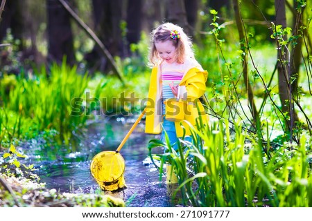 Child playing outdoors. Preschooler kid catching frog with colorful net. Little girl fishing in a forest river. Adventure kindergarten day trip into wild nature, explorer hiking and watching animals.