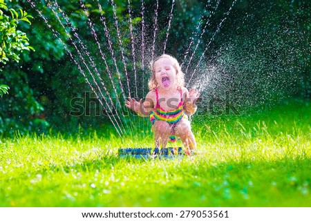 Child playing with garden sprinkler. Kid in bathing suit running and jumping. Kids gardening. Summer outdoor water fun. Children play with gardening hose watering flowers.