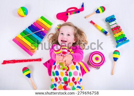 Child with music instruments. Musical education for kids. Colorful wooden art toys for kids. Little girl playing music. Kid with xylophone, guitar, flute.