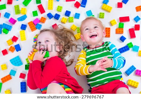 Child playing with colorful toys. Little girl and baby boy with educational toy blocks. Children play at day care or preschool. Mess in kids room. View from above.