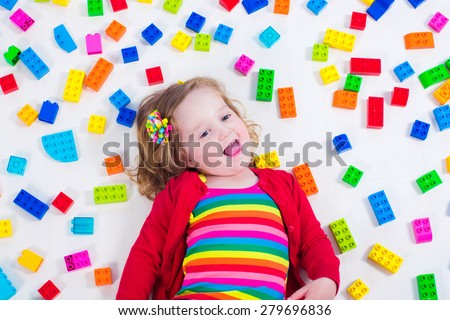 Child playing with colorful toys. Little girl with educational toy blocks. Children play at day care or preschool. Mess in kids room. View from above.